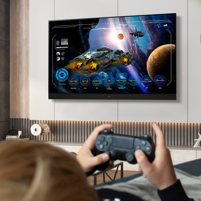 Person spielt ein Sci-Fi-Videospiel auf einem großen Fernseher im modernen Wohnzimmer  Person spielt ein Sci-Fi-Videospiel auf einem großen Fernseher im modernen Wohnzimmer