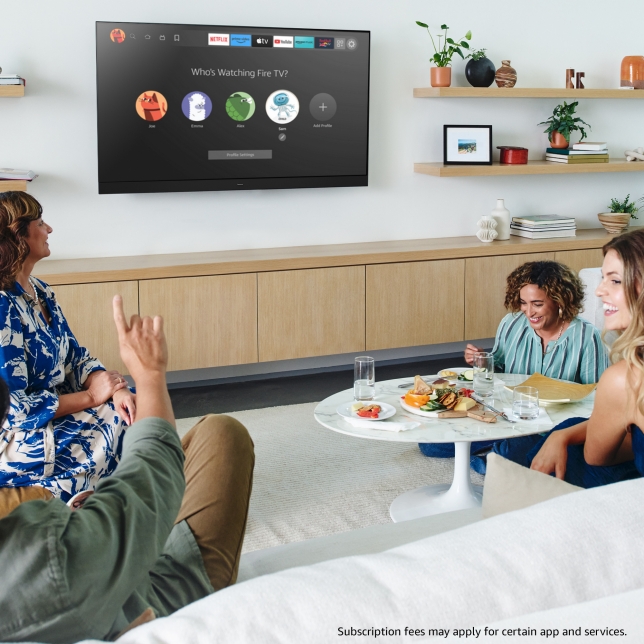 Vier Personen sitzen in gemütlicher Wohnzimmeratmosphäre vor einem Fernseher Vier Personen sitzen in gemütlicher Wohnzimmeratmosphäre vor einem Fernseher