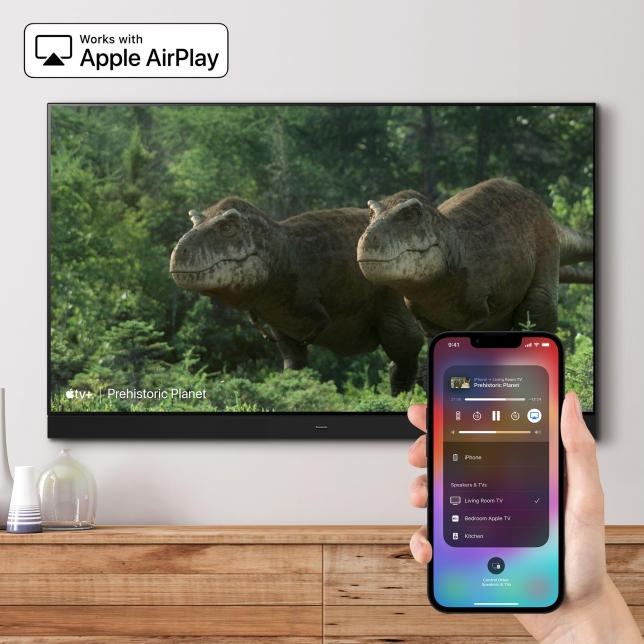 TV zeigt eine Doku-Szene mit Dinosauriern, während ein iPhone Inhalte per Apple AirPlay auf den Bildschirm überträgt. TV zeigt eine Doku-Szene mit Dinosauriern, während ein iPhone Inhalte per Apple AirPlay auf den Bildschirm überträgt.